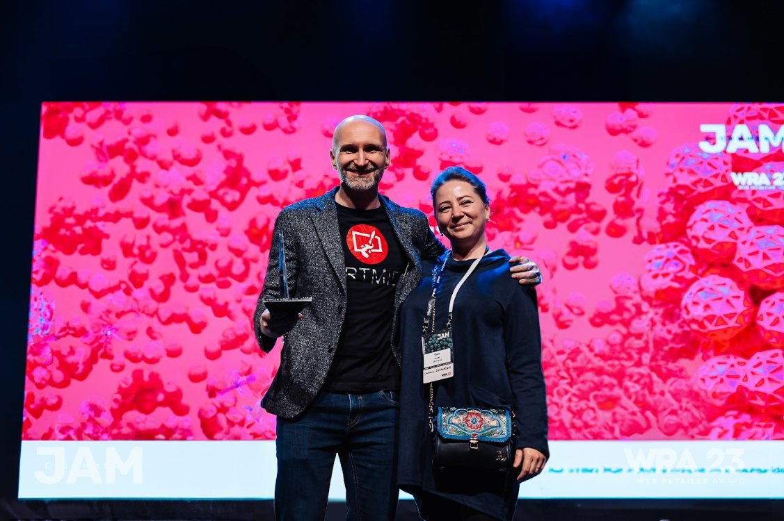 Valerian and Dana Grass on stage at the Web Retailer Award 2023, holding the trophy